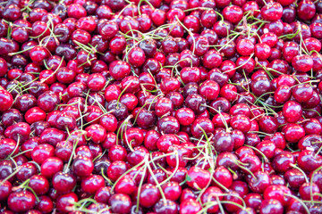 Closeup of fresh cherry fruit. A heap of fresh red ripe sweet cherry berries on a retail market stall. Carmel Market, Tel Aviv, Israel