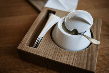 Beautiful sugar bowl on the brown table in the cafe. Close up.