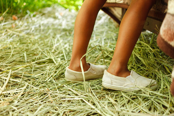Legs of a child in a white sneakers staying on the green grass
