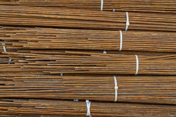 Top view close up stack of straight old rusty high yield stress mild reinforcement steel or iron bars bundle. Background horizontal random pattern from bunch of mild steel bars. 