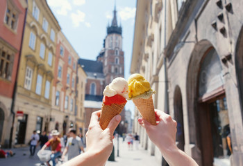 Fototapeta Women's hands with ice cream on the background of the city sights Mariatsky church in the historical center of Krakow, Poland, Europe, a famous tourist place obraz
