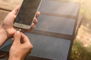smartphone charged by solar panel outdoor on wooden table