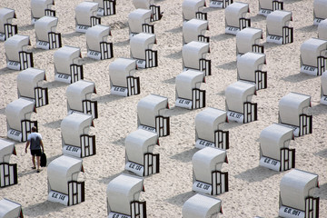 Obraz premium Lonely man amongst lined up beach chairs, Baltic Sea
