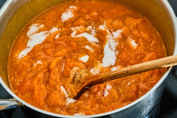 Stiring sugar in white cooking apricots
