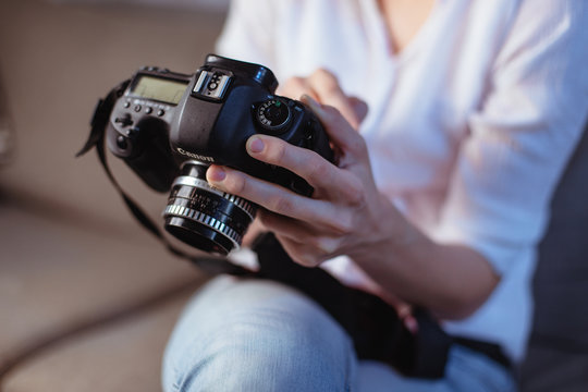 A young female photographer in the evening at home reviewing photos on the camera
