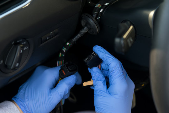 Thief In Gloves Is Trying To Start The Car With Wires Under The Steering Wheel, Close-up