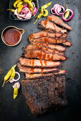Traditional smoked barbecue wagyu beef brisket offered as top view on an old rustic board with...