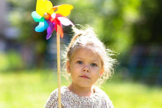 Child with Pinwheel in the summer park looking at camera