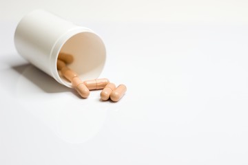 Close Up on vitamins and supplements on pure white background with a brown and white bottle
