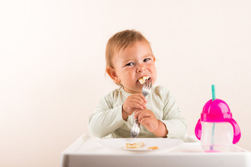 Baby toddler eating pancakes with fork. Isolated. Copy space