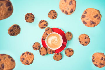 Coffee cup woth flying cookies over blue background.