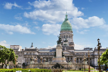 Front view of the National Congress building in Buenos Aires, Argentina, surrounded by green trees, against a blue summer sky.