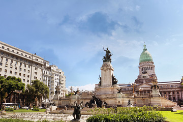 View of the National Congress building in Buenos Aires, Argentina, surrounded by green trees, against a blue summer sky.