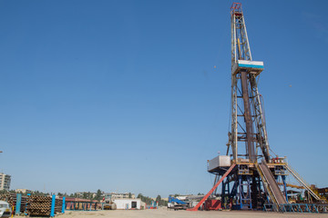 Fototapeta premium Land oil drilling rig blue sky .Land rig during the drilling operation . Oil and gas drilling rig onshore dessert with dramatic cloudscape .