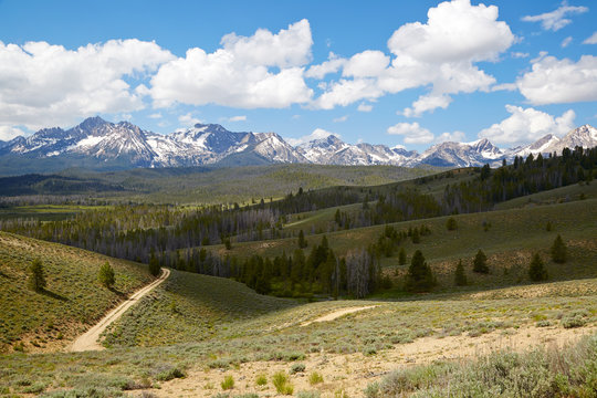 Sawtooth Mountain range on summer day with green rolling hills and blue sky in Idaho