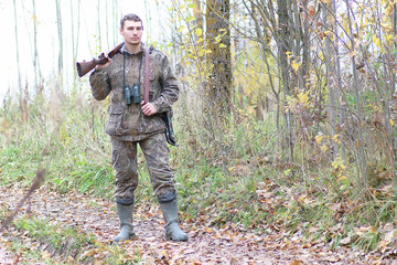 Man in camouflage and with guns in a forest belt on a spring hunt