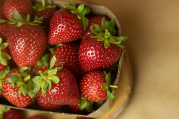 Fresh strawberries in a Kraft box on a wooden stand close-up. Open space, healthy food concept, plants, soil, organic natural products, natural food, vegetarian dishes, vegetables, raw, food festival