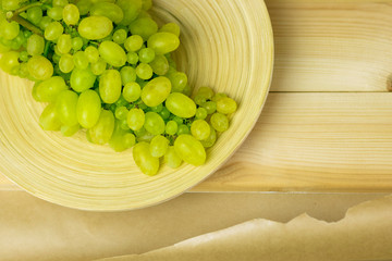 Bowl with green grapes on a wooden stand close-up. Healthy food concept, plants, soil, organic natural products, natural food, vegetarian, vegetables, raw, food festival