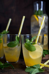 Homemade orange lemonade with citrus and mint on a dark wooden background