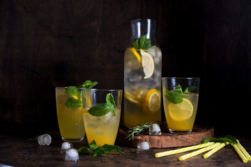Homemade orange lemonade with citrus and mint on a dark wooden background