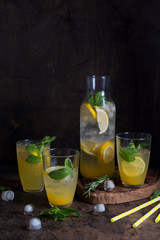 Homemade orange lemonade with citrus and mint on a dark wooden background
