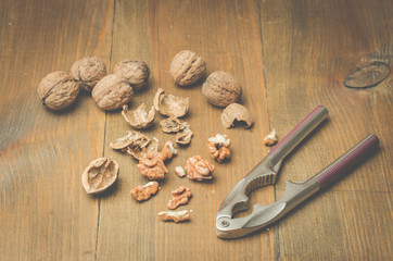 Walnut. A shell and nutcracker on a wooden background. Top view
