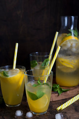Homemade orange lemonade with citrus and mint on a dark wooden background