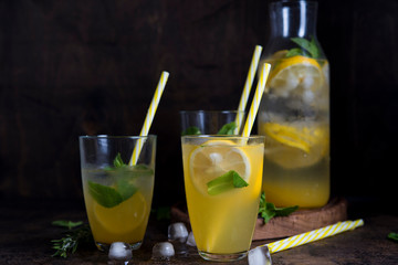 Homemade orange lemonade with citrus and mint on a dark wooden background