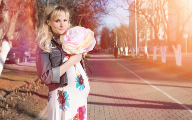 Pregnant girl on a walk in the park. Girl with a belly in the city park. The future mom is walking in the park.