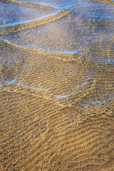 Ripples on water forming pattern of shadows on the sand beneath