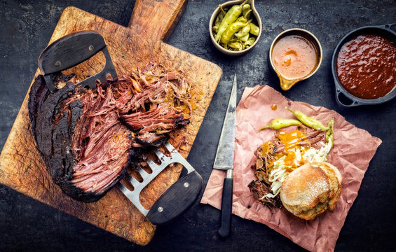 Traditional barbecue wagyu pulled beef with coleslaw and sandwich as top view on a rustic cutting board