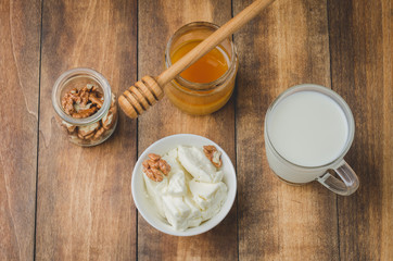 Fototapeta na wymiar Healthy breakfast background. Honey, milk, cottage cheese and walnut on a wooden background. Top view.