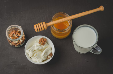 Healthy breakfast background. Honey, milk, cottage cheese and walnut on a stone background. Top view.