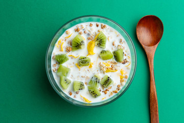 Glass bowl with cornflakes and milk on a green background, top view