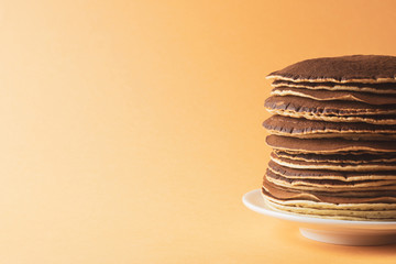 Pancakes on a saucer on an orange background, closeup