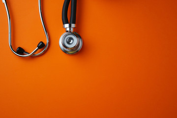 Medical stethoscope on orange background