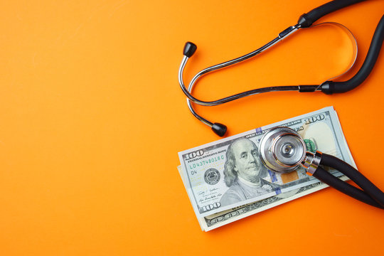 Medical stethoscope and money on orange background