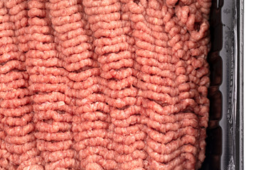 Raw Hamburger Meat in a Plastic Package on a White Background