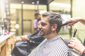 Men hairstyling and haircut in a barber shop or hair salon.