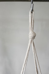 A very simple knotted cotton string looped and hanging on a hook.