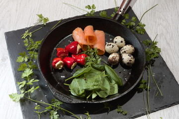 ketogenic food in a cast-iron frying pan with scrammbled quail eggs pepperoni cream cheese spinach...