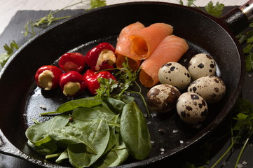 ketogenic food in a cast-iron frying pan with scrammbled quail eggs pepperoni cream cheese spinach...
