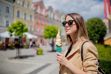 style woman in sunglasses and ice-cream in aged city center square.