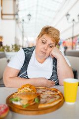 Fatty woman eating pizza in fastfood restaurant