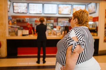 Fototapeta na wymiar Fat woman at the fast food restaurant menu