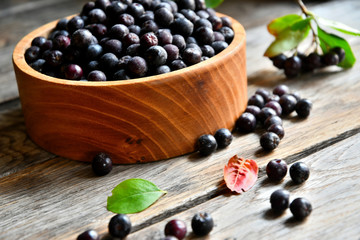 Black chokeberry in wooden utensils on old wooden boards.