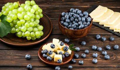 Fototapeta na wymiar .cheese and blueberries with grapes on a wooden background