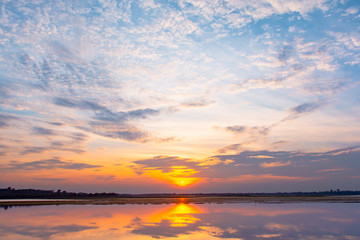 Sunset reflection lagoon. beautiful sunset behind the clouds and blue sky above the over lagoon landscape background. dramatic sky with cloud at sunset