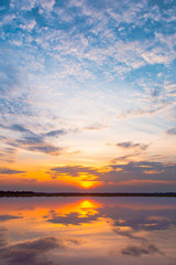 Sunset reflection lagoon. beautiful sunset behind the clouds and blue sky above the over lagoon landscape background. dramatic sky with cloud at sunset