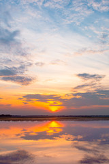 Sunset reflection lagoon. beautiful sunset behind the clouds and blue sky above the over lagoon landscape background. dramatic sky with cloud at sunset